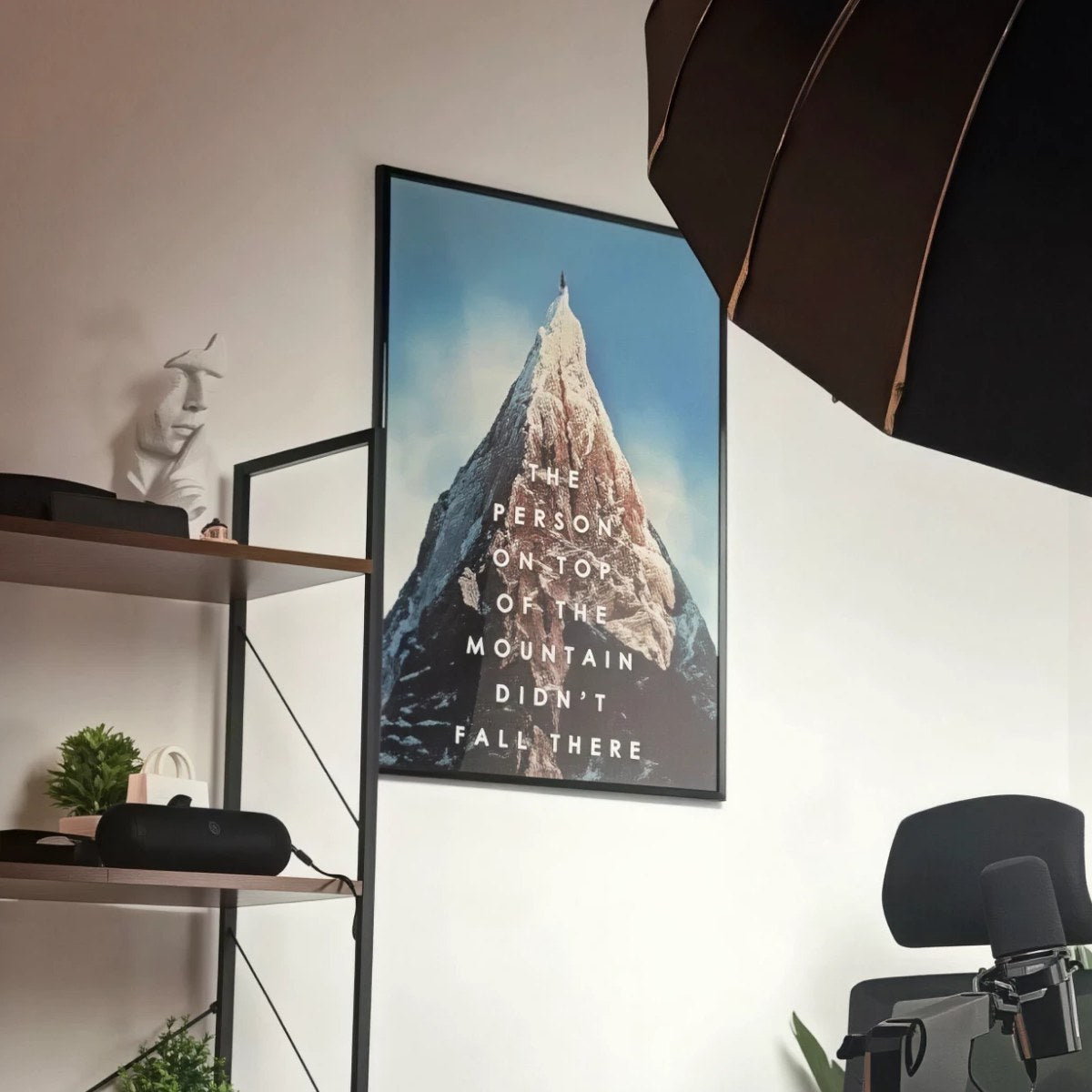Póster ON TOP con marco negro en la pared de un estudio, con un foco, una estantería, una silla y un micrófono